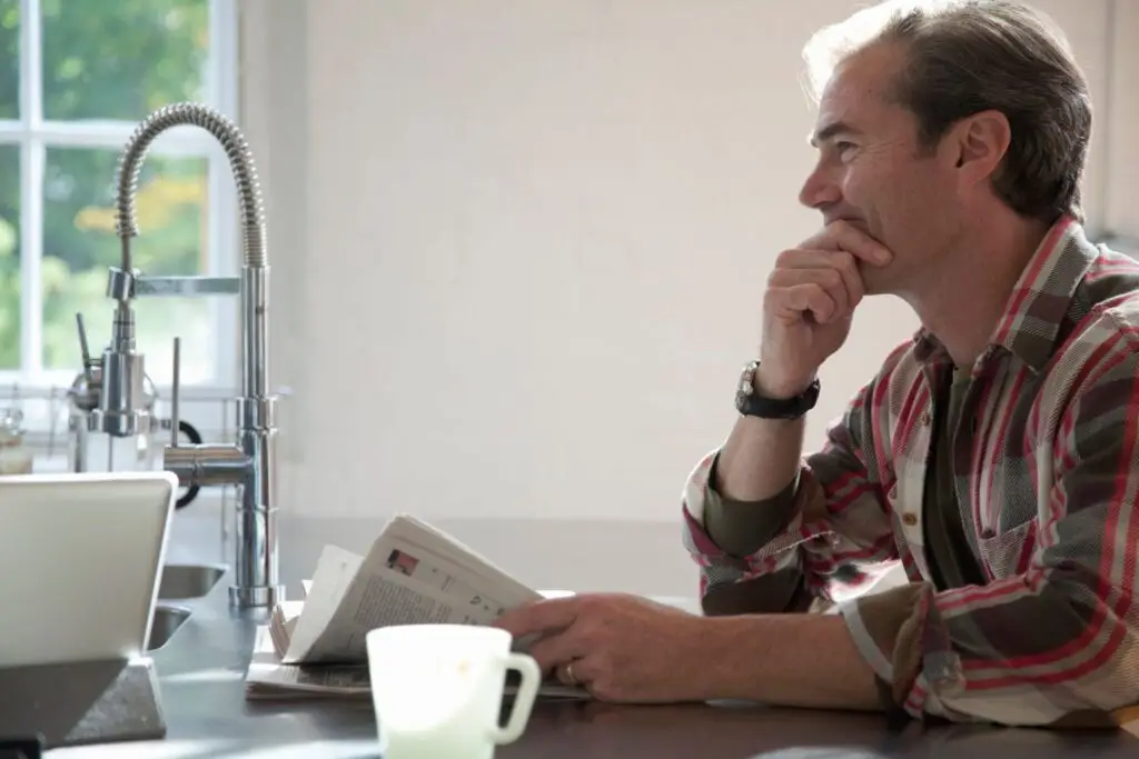 A man sitting at a kitchen table while thinking about water softener costs and water treatment options