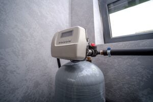 Water softener system connected to residential plumbing pipes inside a home utility area